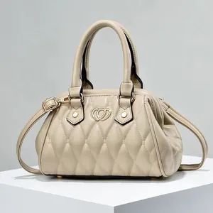 Bolso bandolera beige acolchado con logo de corazón sobre un soporte geométrico