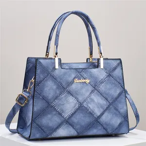 Blue denim quilted tote bag with large diamond stitching and metallic top handles