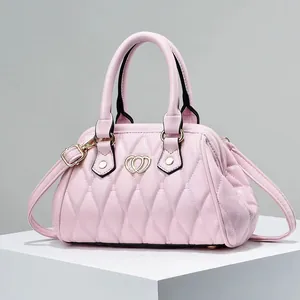 Bolso Boston acolchado rosa con hebilla de corazón dorada en soporte blanco minimalista