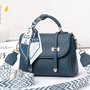 Détail du sac en cuir grainé bleu sarcelle avec poignée foulard et bandoulière motif