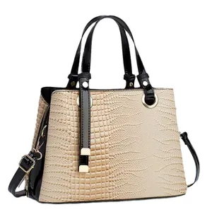 Chic beige crocodile embossed handbag with black patent leather trim and gold hardware