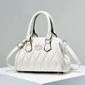 Detalle de bolso acolchado blanco con hebilla de corazón dorado en base minimalista