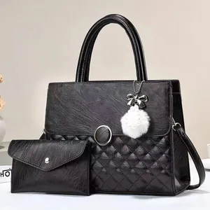Detail of black quilted tote bag and matching clutch with pearl fur pompom charm