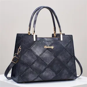 Detailed macro view of diamond-quilted denim texture and gold hardware on blue tote bag