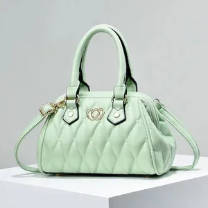Detalle del bolso acolchado de cuero verde menta con logotipo de corazón dorado