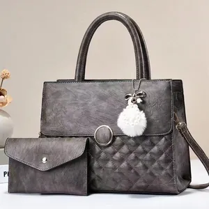 Close-up of gray quilted tote bag with pearl fur ball charm and matching wallet