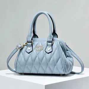 Detalle del bolso acolchado azul claro con cierre de corazón dorado en expositor