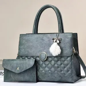 Detail view of teal quilted leather tote bag set with metal ring and plush pompom charm