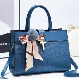 Détail du sac à main bleu motif croco avec fermoir doré en T et foulard en soie