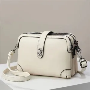 Detail view of beige lychee textured PU crossbody bag with triple zipper layers