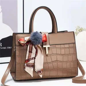 Détail du sac à main marron motif crocodile avec boucle dorée et accessoire de foulard