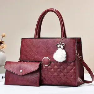 Detail of burgundy quilted tote and envelope clutch bag set with metallic ring accent