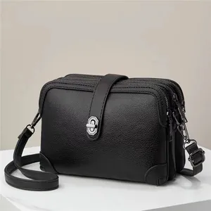 Close-up of black litchi pattern leather crossbody bag with three zipper layers