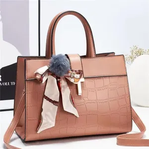 Détail du sac à main rose clair à motif pierre avec foulard en soie et pompon
