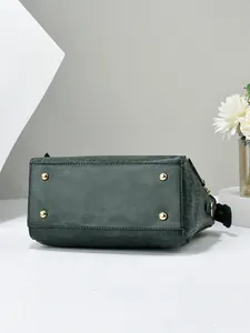 Detail view of the green crocodile texture handbag base with four golden metal protective feet