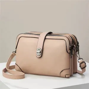 Detailed view of beige crossbody bag featuring triple zipper compartments and lychee texture