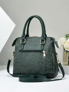 Detailed close-up of dark green embossed crocodile pattern leather bag with gold hardware