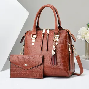 Brown crocodile embossed tote bag set with matching wallet and cat charm on a pedestal