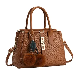 Brown woven tote bag with luxury embossed texture and stylish cherry fur pom-pom charm