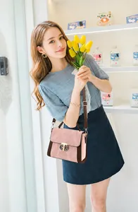 Detail van de goudkleurige bloemsluiting en contrasterende stiksels op de handtas