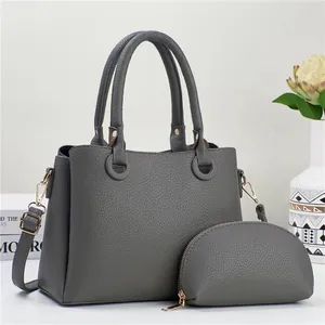 Detail of dark grey lychee leather tote bag with matching zipper pouch and gold hardware