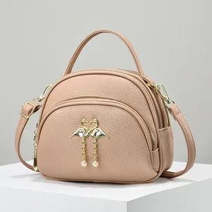 Petit sac bandoulière rose en cuir avec boucle cœur flamant et double fermeture éclair