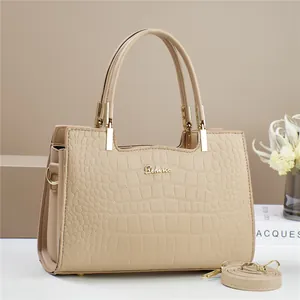 Close-up of beige crocodile pattern tote bag with gold metal logo and shoulder strap