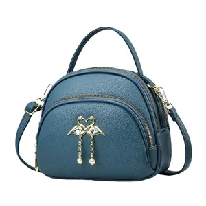 Petit sac rond bleu foncé avec fermoir flamant rose doré et détail de gland en perles