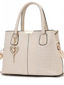 Détail du sac à main beige en cuir grainé avec broderie élégante et pendentif perle