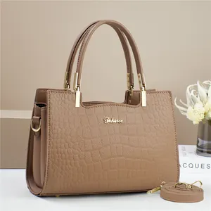 Detail of crocodile embossed leather tote bag with gold logo and detachable shoulder strap