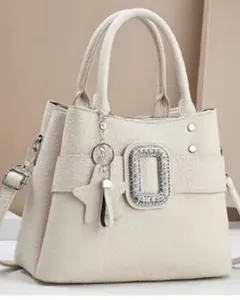Detail view of cream leather tote with rhinestone buckle and star charm tassel