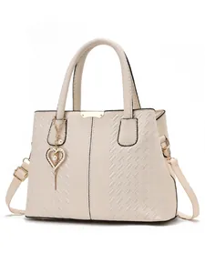 Détail du sac crème avec texture tissée et breloque en forme de cœur avec perle
