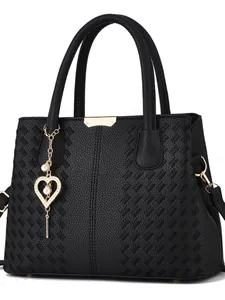Détail d'un sac bandoulière noir avec texture matelassée, pendentif coeur et perles