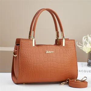 Close-up of brown crocodile pattern handbag with gold hardware and Dekerce logo detail