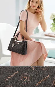 Détail de la texture en cuir PU et du pendentif cœur sur le sac à main marron