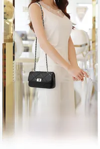 Detail of black quilted leather crossbody bag with silver chain and rotary metal lock