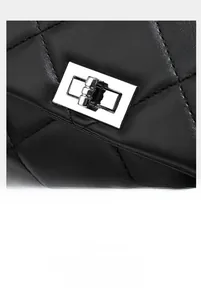 Macro shot of silver rectangular twist lock and quilted stitching on black leather bag
