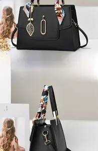 Dettaglio borsa in pelle nera con manico in seta colorata e ciondolo a foglia dorata