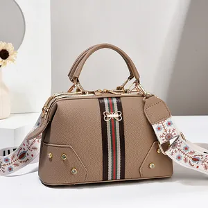 Vue détaillée du sac à main kaki avec sangle verte et rouge et bandoulière brodée