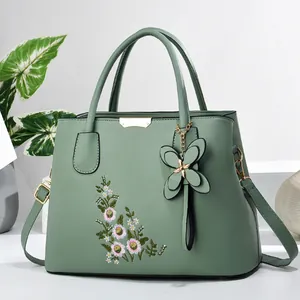 Detail of floral embroidery and gold hardware on sage green leather handbag for women