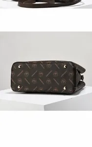Détails du sac cabas marron montrant les clous de protection et le motif monogramme