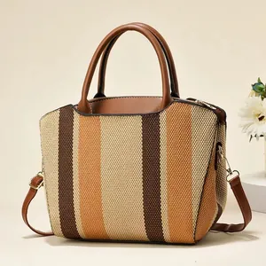 Detail of striped canvas tote showing brown leather handles and golden metal hardware