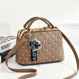 Sac à main marron matelassé avec clous dorés, pompon et bandoulière réglable