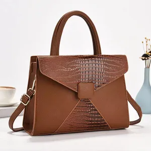 Détail d'un sac à bandoulière marron en patchwork avec textures litchi et crocodile