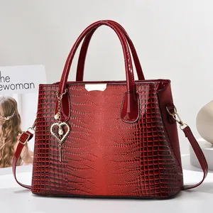 Détail du sac à main rouge foncé à motif crocodile et breloque coeur perlé doré