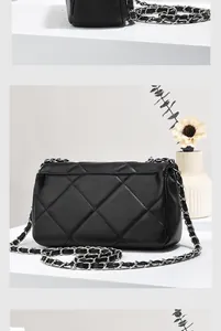 Detail of black quilted leather crossbody bag with silver chain strap on minimalist background