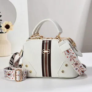 Détail du sac Boston blanc avec cuir litchi, ruban et boucle dorée élégante en gros plan