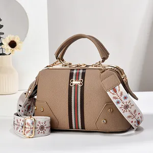 Détail du sac en cuir grainé avec ruban, nœud en métal et bandoulière bohème