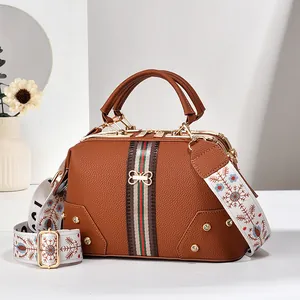 Détails d'un sac docteur en cuir marron avec rayures rétro et bandoulière brodée