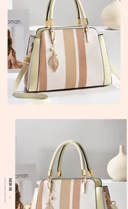 Detail der Retro-Streifen-Handtasche mit Ledergriff und goldenem Blatt-Metallanhänger